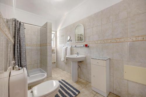 a bathroom with a toilet and a sink and a tub at Brisa do Mar in Carvoeiro