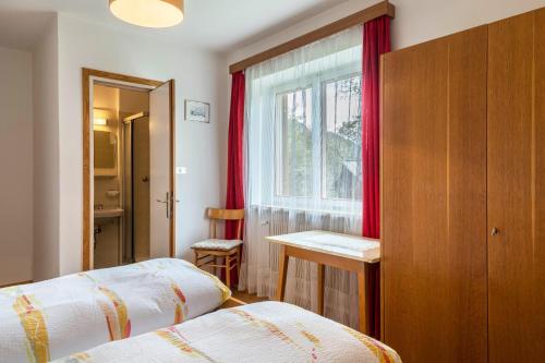 a bedroom with two beds and a window with red curtains at Cësa Gravina Jubas in Ortisei