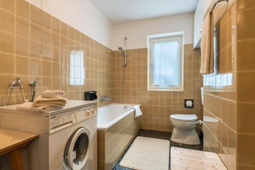 a bathroom with a washing machine and a toilet at Cësa Gravina Jubas in Ortisei