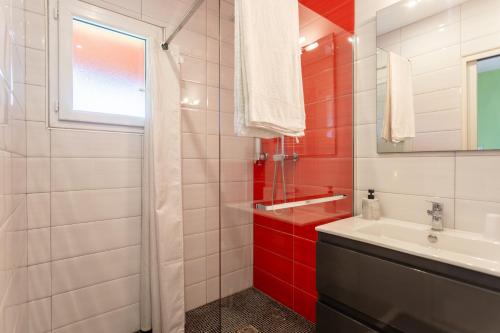 a red and white bathroom with a sink and a mirror at Chambre - Lis in Aroue