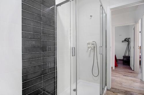 a shower in a bathroom with black tiles at Casa da Padaria in Leiria
