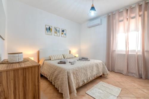 a white bedroom with a bed and a window at Albachiara Sul Mare in Porto Torres