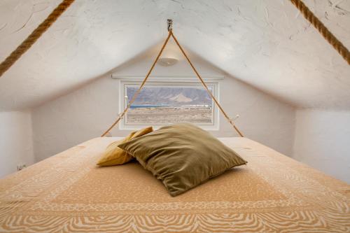 a bed with a pillow in a room with a window at El Loft in Famara