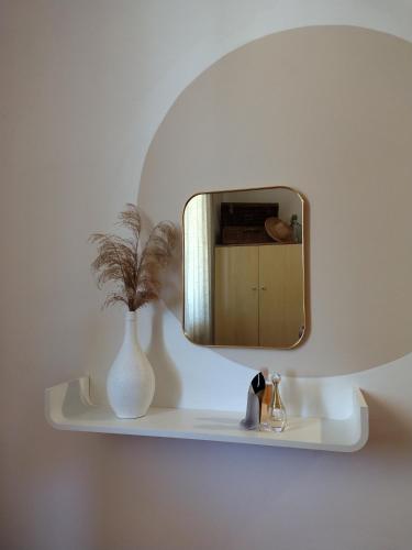 a mirror on a wall with a vase on a shelf at Meridiana case al mare in Mattinata
