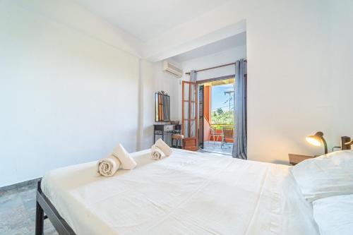 a white bedroom with two beds and a balcony at Arianna Studio Ground Floor 3 in Paleokastritsa