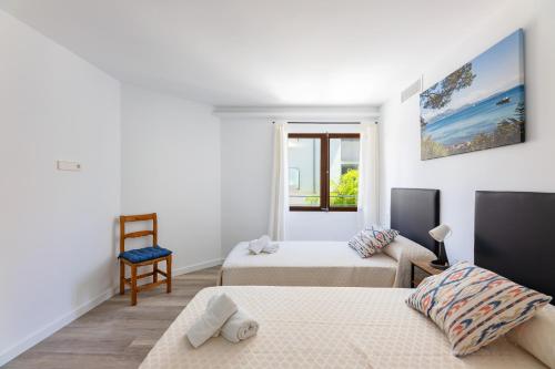 a white room with two beds and a chair at Albercutx Pollentia 1 2 3 in Pollença
