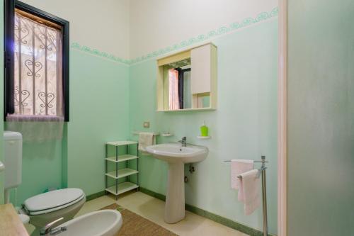 a green bathroom with a sink and a toilet at Domus mea salento Arazzo Giallo in Ugento