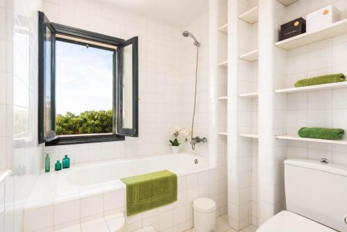a white bathroom with a tub and a window at Villa Es Gallinots in Mahón