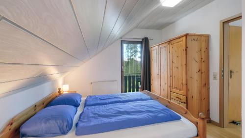 a bed with blue pillows in a room with a window at Waldfee - Stilvolles Ferienhaus in Kemmerode