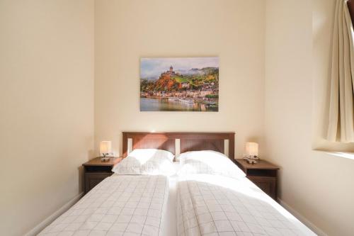 a bedroom with a white bed with a painting on the wall at Alte Stadtvilla am Weinberg 2 in Traben-Trarbach