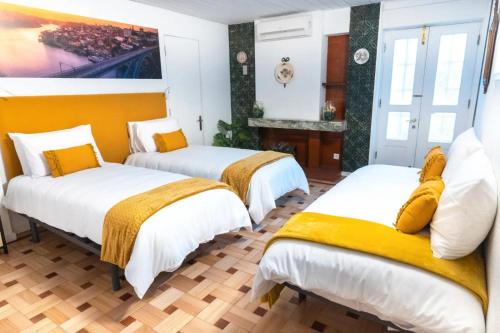 a room with three beds with yellow and white sheets at Douro Garden Home Rooftop in Vila Nova de Gaia
