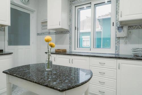 a kitchen with a vase with yellow flowers on a counter at Douro Garden Home Rooftop in Vila Nova de Gaia