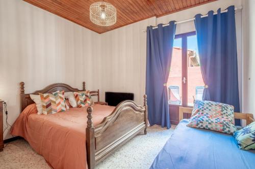 a bedroom with a bed and a window with blue curtains at Maison de pecheurs in Valras-Plage