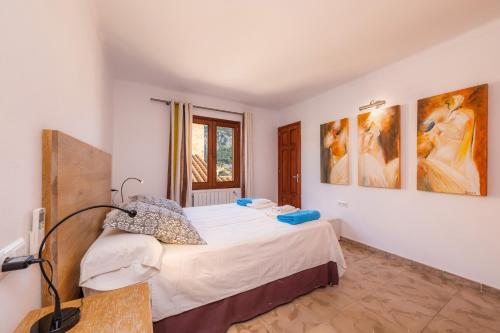 a bedroom with a bed and some paintings on the wall at Casa Coronel Aloy in Pollença
