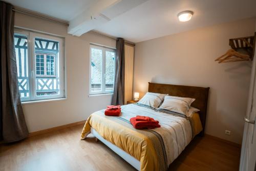 a bedroom with a bed with two red towels on it at Murmures de la Risle in Pont-Audemer