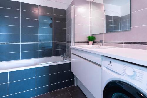 a washing machine in a bathroom with blue tiles at Appartement T2 Muses in Le Crès