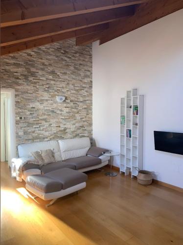 a living room with a couch and a brick wall at Il Rifugio di Palmanova in Palmanova