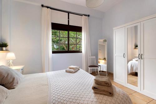a white bedroom with a bed and a window at La Huerta in Hermigua