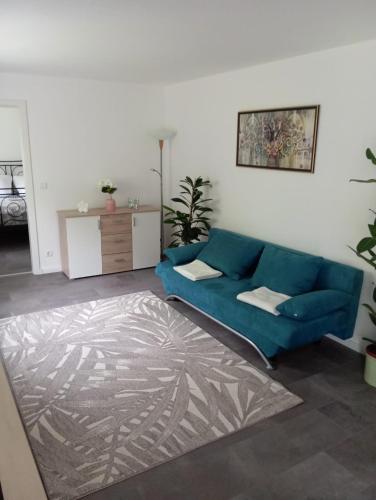 a living room with a blue couch and a rug at Villa am Bacho in Dörzbach