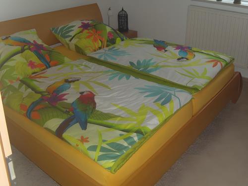 a bed with a colorful comforter with birds on it at Ferienhaus Kudensee in Kudensee