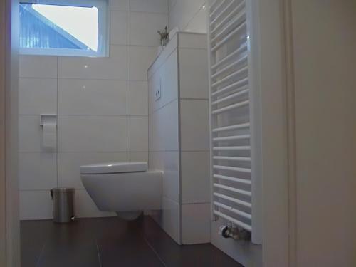 a white bathroom with a toilet and a window at Ferienhaus Kudensee in Kudensee