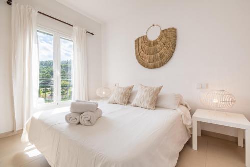 a white bedroom with a large white bed and a window at Soller beach apartment in Sóller
