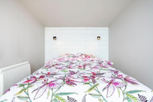 a white bedroom with a bed with a floral bedspread at Maison de vacances proche de tout in Quimper