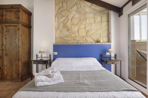 a bedroom with a large bed with a blue wall at Casa Las Niñas in Olvera