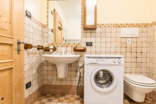 a bathroom with a toilet sink and a washing machine at Maso Noce Est in Mezzana