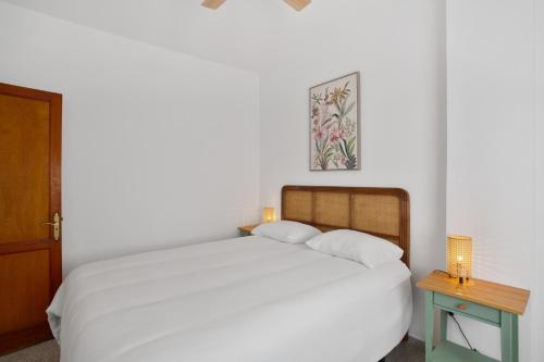 a bedroom with a white bed with a nightstand and a table at Apartamento Danoe 5 in Mogán
