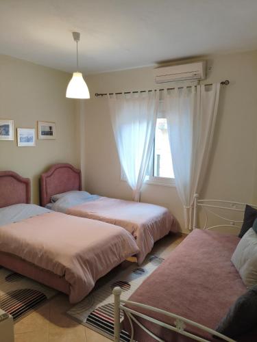 ein Zimmer mit drei Betten und einem Fenster in der Unterkunft Pylos before midnight in Pylos
