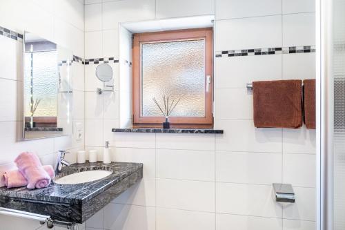 a white bathroom with a sink and a window at Alpenblick Tilly - Fewo Soiernsee 4 in Krün