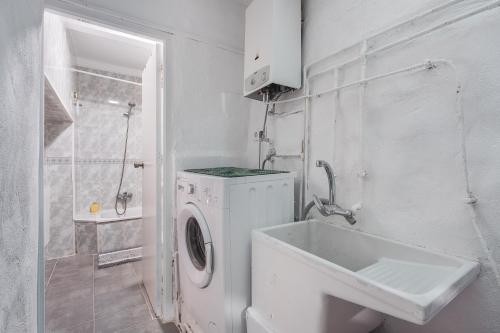 a white bathroom with a washing machine and a sink at Alicia's House in Granada