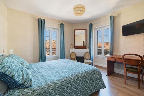 a bedroom with a bed and a desk and windows at Appartement Graingalet in Carbonne