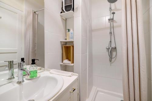 a white bathroom with a sink and a shower at Appartement Graingalet in Carbonne