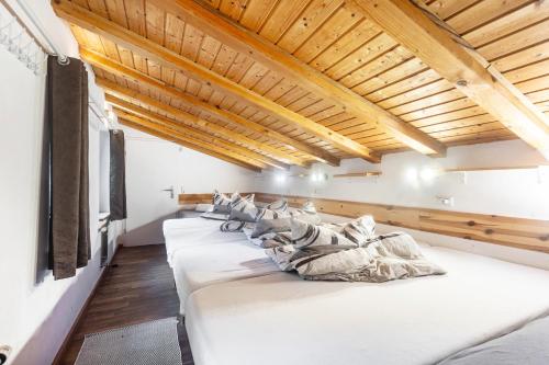 a row of white beds in a room with wooden ceilings at Großes Ferienhaus Engelsdorf in Zweifelscheid