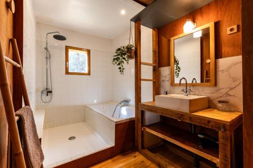 a bathroom with a tub and a sink and a bath tub at Les Ptis Chiffons in Lacanau
