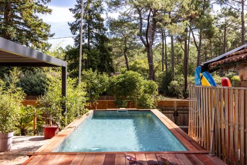 uma piscina em um quintal com deck de madeira em Les Ptis Chiffons em Lacanau