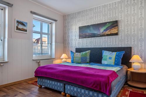 a bedroom with a purple bed with two windows at Ferienwohnung Blütenzauber in Sagard