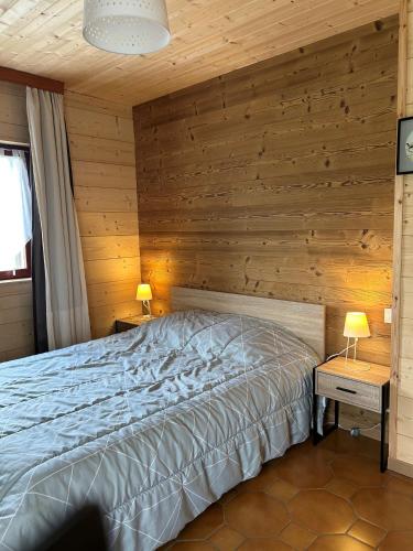 a bedroom with a bed and a wooden wall at Location Vacances Des 4 Vents in Girmont-Val-dʼAjol