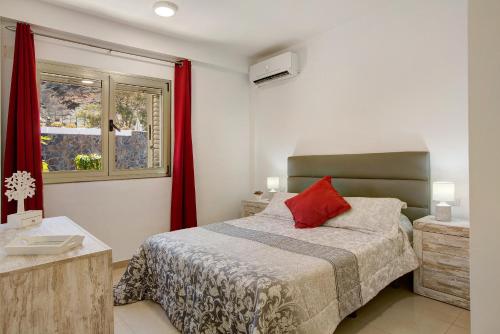 a bedroom with a bed and a window with red curtains at Ca Luis in Mogán
