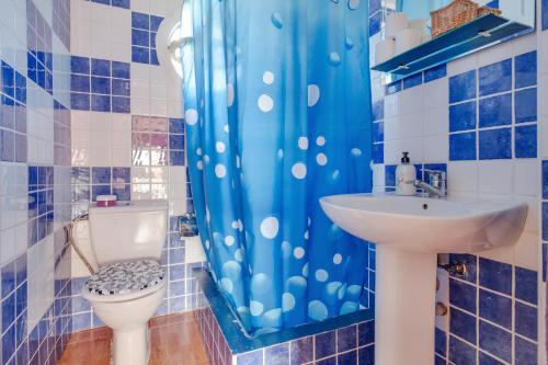 a bathroom with a blue shower curtain and a toilet at La Casa De Enzo in Playa de las Americas