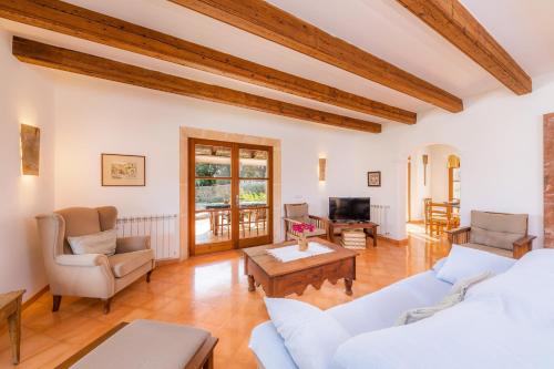 a living room with white furniture and wooden ceilings at Can Xisco in Artá