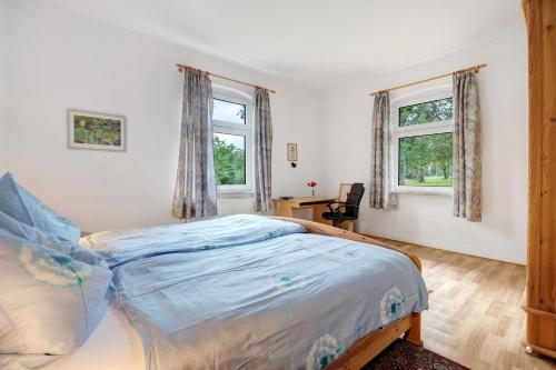 a bedroom with a bed and two windows at Ferienhaus Feldblick in Karwitz