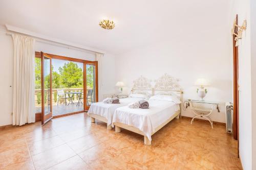 a white bedroom with a bed and a balcony at Tomymar in Cala Ratjada