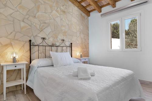 a bedroom with a large bed and a stone wall at Casa Faquinse La Muela 1 in Vejer de la Frontera