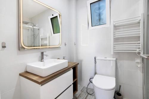 a bathroom with a sink and a toilet and a mirror at White Studio and Terrace in Albufeira