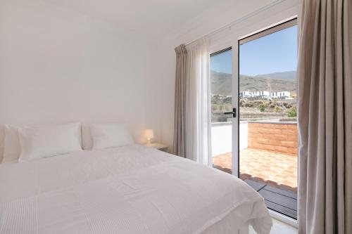 a bedroom with a white bed and a large window at Private Villa Candelaria in Candelaria