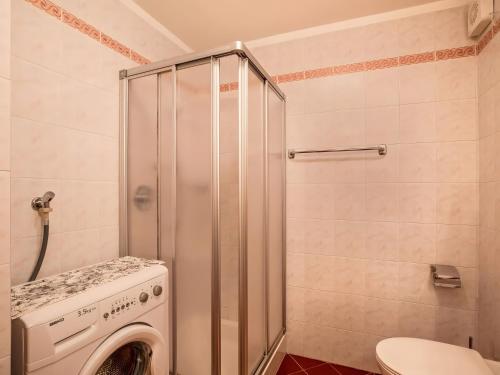 a bathroom with a washing machine and a toilet at Ciasa Lino Aloch in Pozza di Fassa