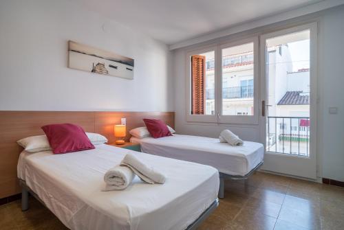 two beds in a room with two windows at Canet beach 3 in Canet de Mar